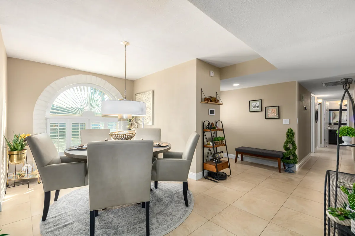 A cozy dining area centered around a wooden dining table, enhanced by a stylish light fixture and natural light streaming through window shutters. The setting is ideal for family meals or celebratory toasts after a day’s adventure.