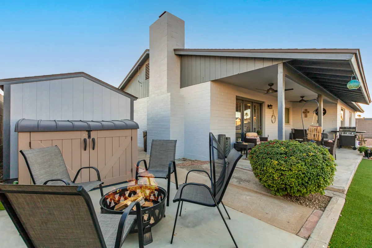 An inviting backyard scene with a fire pit surrounded by cozy seating and lush landscaping. The sunset glow illuminates the space, creating a tranquil environment perfect for evenings spent relaxing or socializing outdoors.