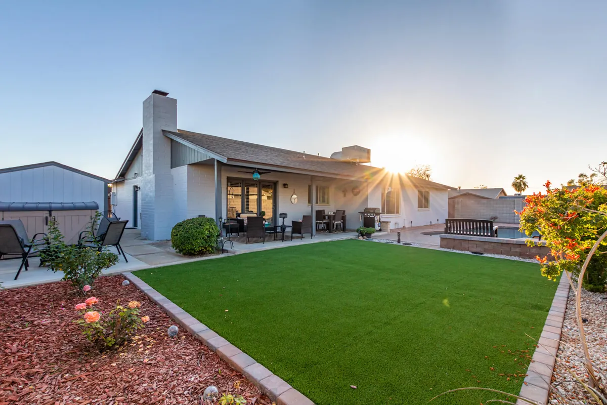 A welcoming backyard with a green lawn, a comfortable seating area, flower beds, and a warm sunset glow. This space is designed for outdoor dining, entertaining, and enjoying the tranquility of the neighborhood.