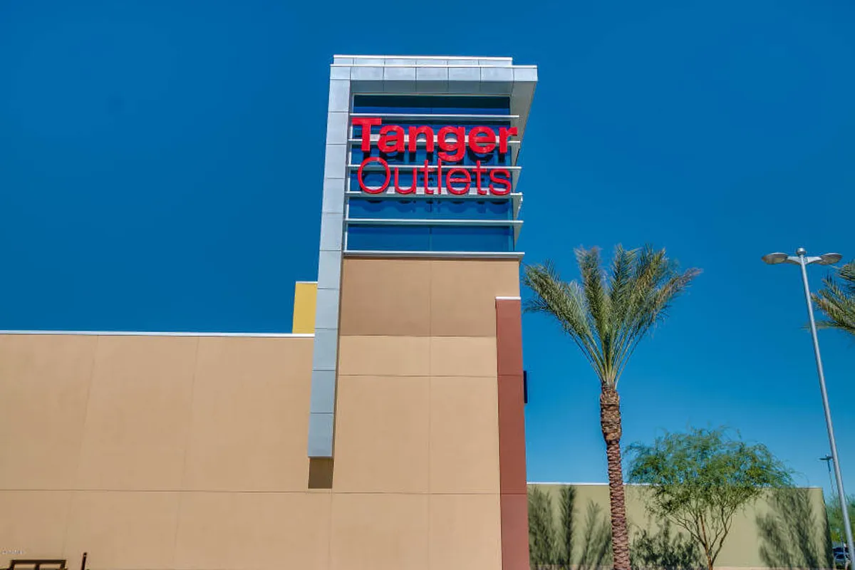 The vibrant exterior of Tanger Outlets, framed by palm trees and modern architecture, illustrates another prominent local attraction for shopping, dining, and gathering before or after games.